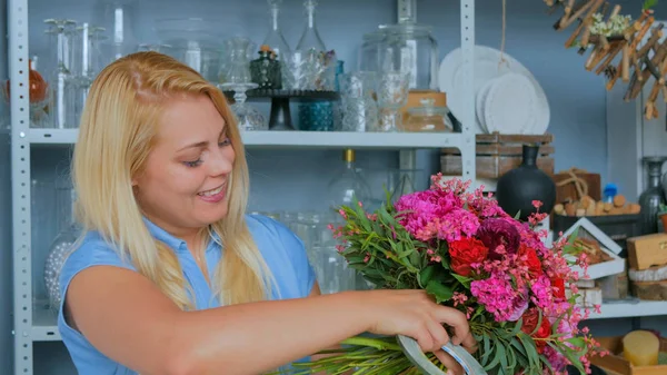 Professional woman floral artist, florist in blue dress making beautiful wedding bouquet at workshop, flower shop. Floristry, handmade and small business concept