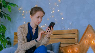 Evde dikey siyah akıllı telefon kullanan bir kadın