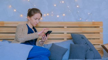 Evde dikey siyah akıllı telefon kullanan bir kadın