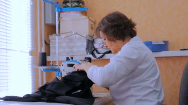 Profesyonel terzi, moda tasarımcısı dikiş makinesiyle elbise dikiyor.