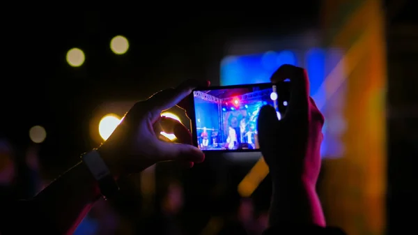 Hands silhouette recording video of live music concert with smartphone