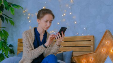 Evde dikey siyah akıllı telefon kullanan bir kadın