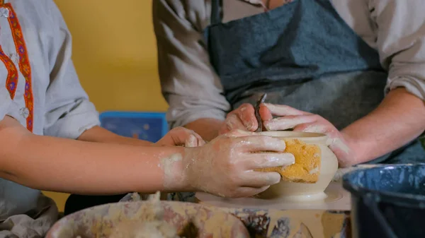 Potter showing how to work with ceramic in pottery studio