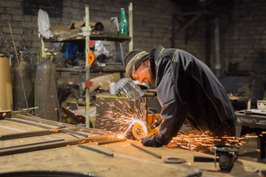 Demirci el testeresiyle metal kesiyor.