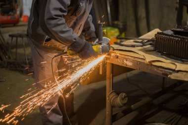 Demirci el testeresiyle metal kesiyor.