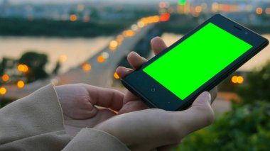 Yeşil ekranlı akıllı telefona bakan kadın