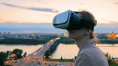 Kadın sanal gerçeklik gözlük güneş battıktan sonra şehirde kullanır