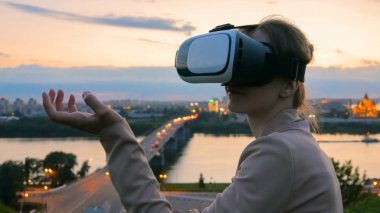 Kadın sanal gerçeklik gözlük güneş battıktan sonra şehirde kullanır
