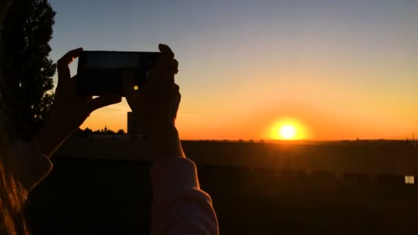 Mujer tomando fotos del atardecer con smartphone en la ciudad — Vídeo de stock