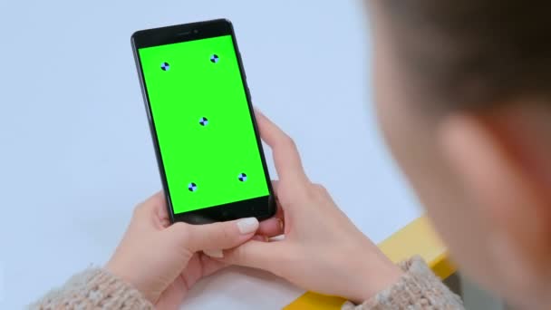 Женщина трогает пустой зеленый экран черного смартфона - жест рукой — стоковое видео