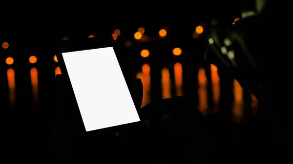 Woman using vertical smartphone with white empty display at night