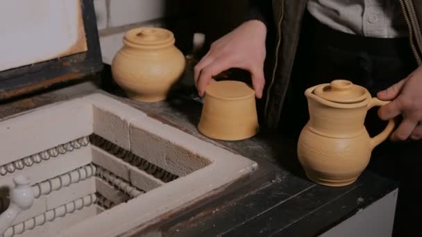 Поттер розміщує керамічні вироби в керамічній печі — стокове відео