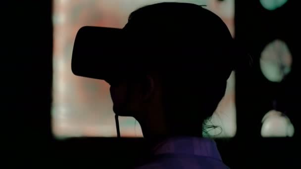 Молодая женщина использует гарнитуру виртуальной реальности на темной интерактивной выставке — стоковое видео