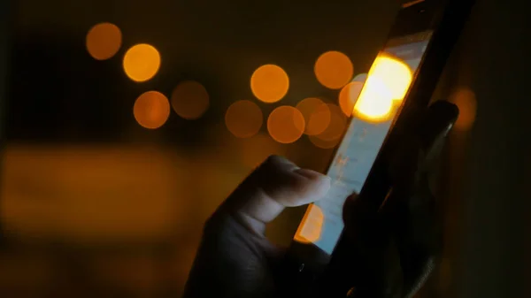 Vrouw die 's nachts verticale zwarte smartphone gebruikt — Stockfoto