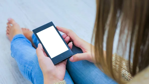 Frau blickt auf Smartphone mit weißem leeren Display Stockbild