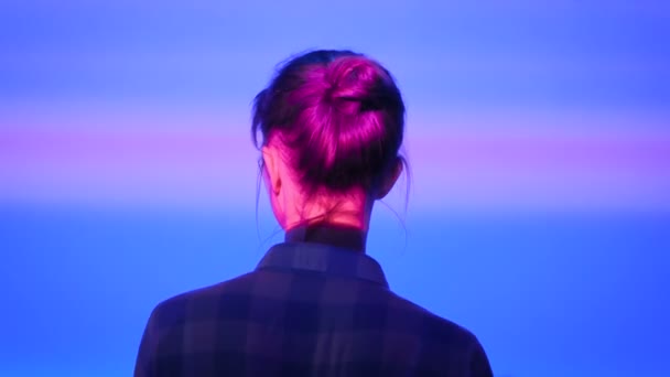 Mujer mirando a su alrededor en la exposición moderna con iluminación de luz multicolor — Vídeos de Stock