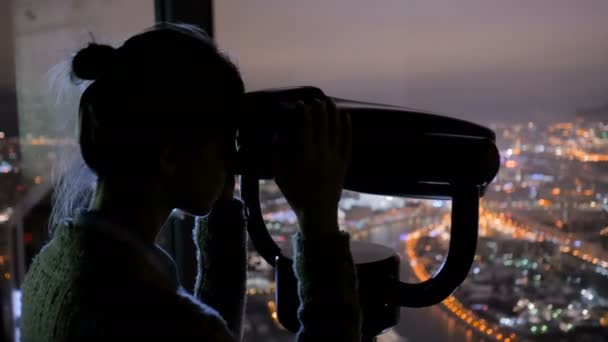 Wanita muda melihat melalui teleskop wisata dan menjelajahi pemandangan kota malam — Stok Video