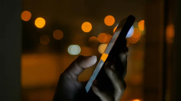 Vrouw die 's nachts verticale zwarte smartphone gebruikt — Stockfoto