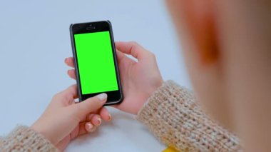 Kadın boş yeşil ekran ile siyah akıllı telefon cihazına bakıyor