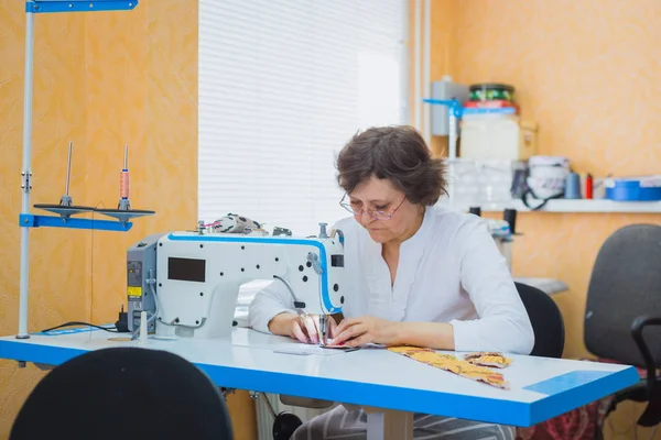Professionele kleermaker naaien kleren met naaimachine bij atelier — Stockfoto