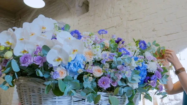 Florist making large floral basket with flowers at flower shop