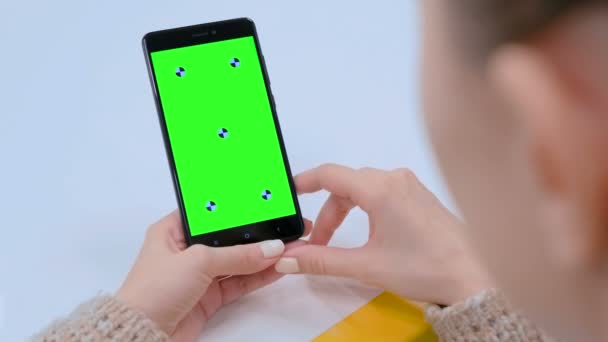 Wanita melihat perangkat smartphone hitam dengan layar hijau kosong — Stok Video