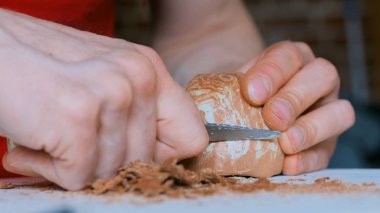 Profesyonel çömlekçi, çömlek atölyesinde özel bir aletle kuru kil bardağı şekillendiriyor.