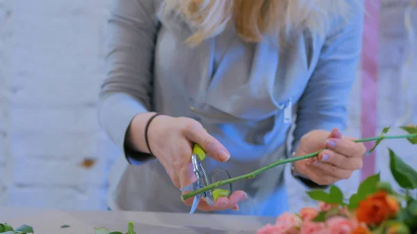 Professional florist cutting flower stems at flower store