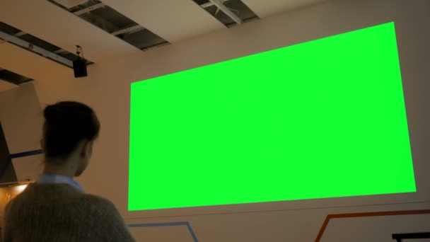 Mulher olhando para grande tela verde em branco - cinema simular — Vídeo de Stock