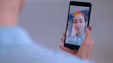 Akıllı telefonda yüz maskesi ile Snapchat Multimedya mesajlaşma uygulamasını kullanan kadın