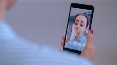 Akıllı telefonda yüz maskesi ile Snapchat Multimedya mesajlaşma uygulamasını kullanan kadın