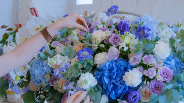 Çiçekçi, çiçekçide büyük bir çiçek sepeti yapıyor.