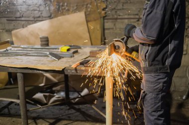 Demirci el testeresiyle metal kesiyor.