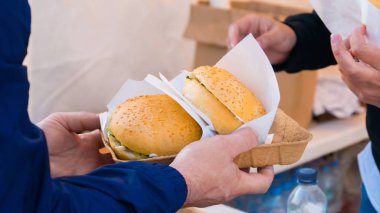 Adam sokak yemekleri festivalinde hamburger yiyor.