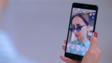 Akıllı telefonda yüz maskesi ile Snapchat Multimedya mesajlaşma uygulamasını kullanan kadın
