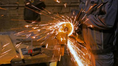 Demirci el testeresiyle metal kesiyor.