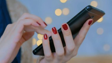 Evde dikey siyah akıllı telefon kullanan bir kadın