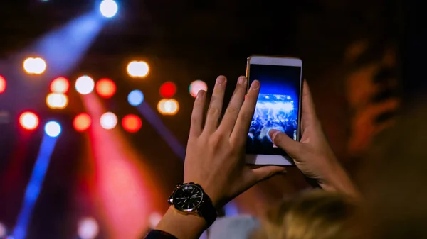 Man hands silhouette recording video of live music concert with smartphone