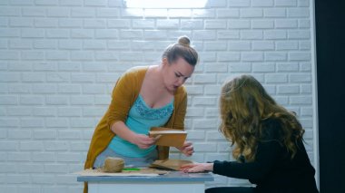 Profesyonel kadın tasarımcı asistana nasıl zarf yapılacağını anlatıyor