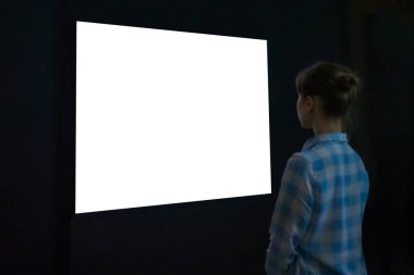 Woman looking at white empty large wall display - mockup image