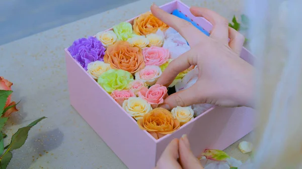 Professional florist making gift box with flowers at flower store