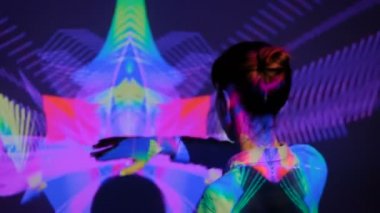 Kadın kollarını sallıyor ve duvarın önünde dans ediyor.