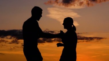 Romantik çift gün batımında dans ediyor.