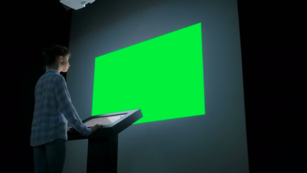 Женщина смотрит на чистый большой интерактивный дисплей стены - концепция зеленого экрана — стоковое видео