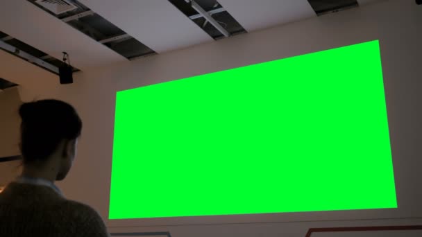 Mujer mirando la gran pantalla verde en blanco - maqueta de cine — Vídeo de stock