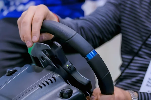 Man using gaming steering wheel joystick at technology exhibition