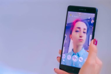 Akıllı telefonda yüz maskesi ile Snapchat Multimedya mesajlaşma uygulamasını kullanan kadın