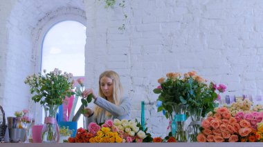 Stüdyoda çiçeklerle çalışan profesyonel bir çiçekçi.