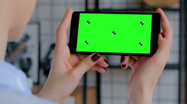 Elinde boş yeşil ekranlı siyah akıllı telefon tutan kadın. Krom anahtar kavramı.