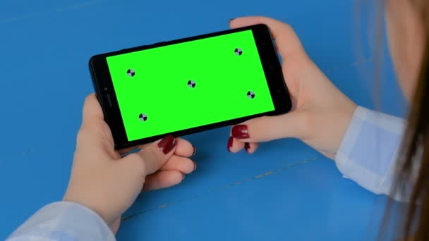 Жінка дивиться на чорний смартфон з порожнім зеленим екраном - концепція ключа хроми — стокове відео